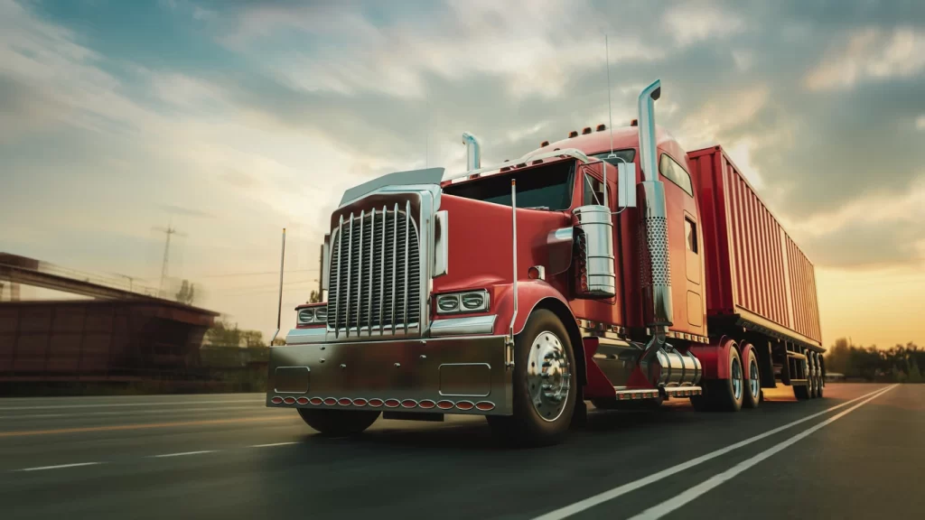 A red big rig truck speeding down the highway at sunset