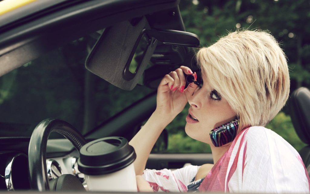 Woman putting on makeup in car