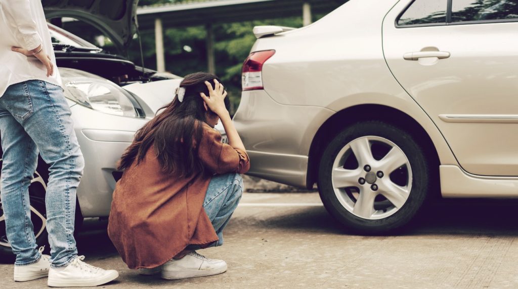 Women checking damages of the rear of her car after a rear-end collision