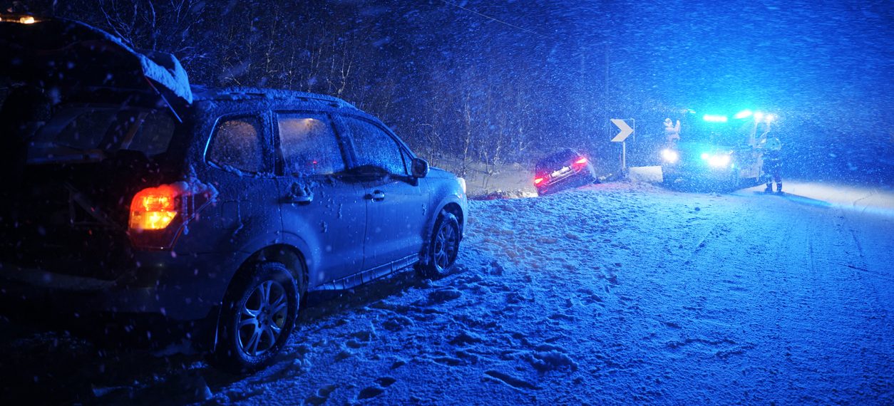 Snow storm at night. Two cars on the side of the road with a tow truck