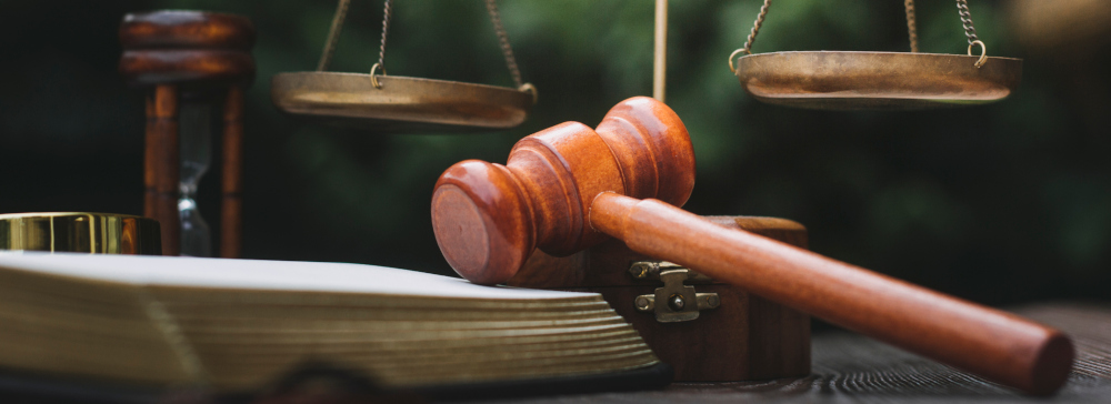 Justice and law concept.Male judge in a courtroom with the gavel, working with, computer and docking keyboard, eyeglasses, on table in morning light